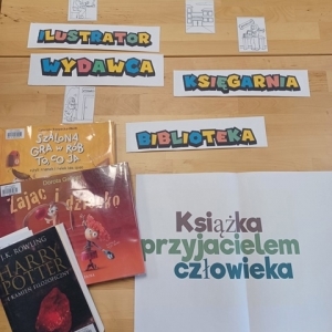 Na stole leżą książki i papierowe napisy