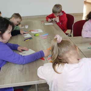 Grupa dzieci, pochylone są nad swoimi pracami.