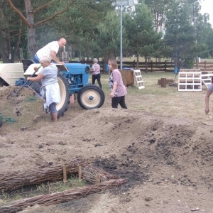 Grupa kobiet i mężczyzna przygotowują miejsce do sadzenia ziół.