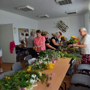 Grupa kobiet stoją przy stole i wybierają rośłiny na bukiet.