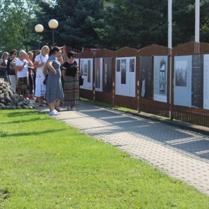 Uczestnicy wyjazdu oglądaja wystawę rozwieszoną na ogrodzeniu 