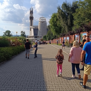 Grupa ludzi idąca drogą, w tle Bazylika Miłosierdzia Bożego.