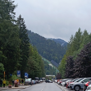 Widok ulicy z samochodami na prakingach w tle skocznia narciarska.