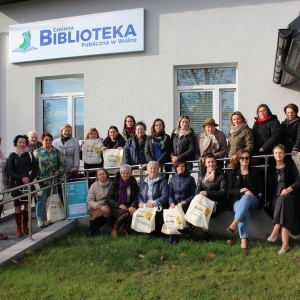 Uczestniczki wyjazdu studyjnego oraz pracownicy biblioteki w Wóce pozują do zdjęcia na pochylni dla osób niepełnosprawnych przed budynkiem biblioteki