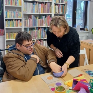 Bibliotekarka trzyma miseczkę z soczewicą, chłopiec sprawdza jakie są jej nasiona w dotyku.