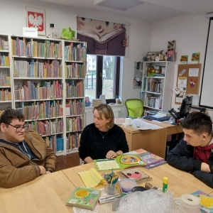 Bibliotekarka czyta książkę, dwóch chłopców jej słucha.