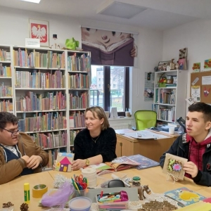 Uczestnicy warsztatów i bibliotekarka prezentują wykonane prace.