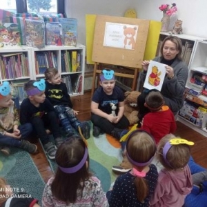 Bibliotekarka pokazuje grupie dzieci portret Kubusia Puchatka