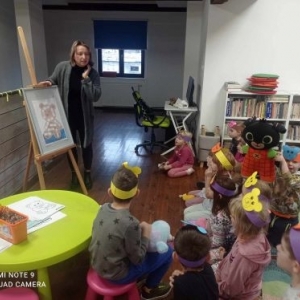 Bibliotekarka tłumaczy grupie dzieci jak wykonać zadanie matematyczne z misiem.