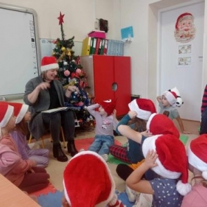 Bibliotekarka czyta dzieciom opowiadanie, gestykuluje przy tym