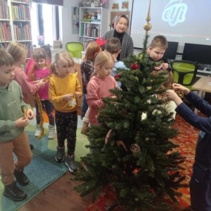 Bibliotekarka z dziećmi stroją choinkę