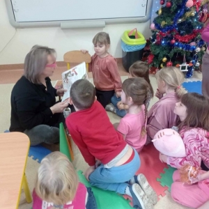 Bibliotekarka w różowych okularach czyta dzieciom książkę