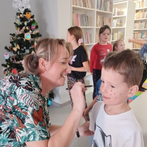 Bibliotekarka maluje chłopcu piegi na twarzy