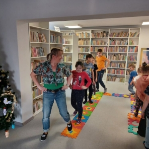 Dzieci maszerują za bibliotekarką, która pokazuje jak mają chodzić