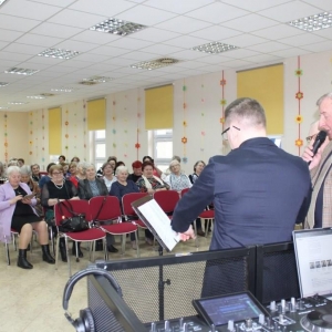 Panowie śpiewaja z karki. Uczestniczki spotkania słuchają.