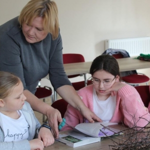 Pani bibliotekarka pokazuje książkę dziewczynkom