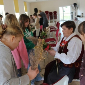 Pani z koła gospodyń pokazuje jakie zioła dobrać do palmy wielkanocnej.