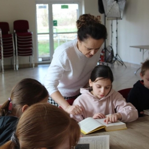 Grupa dzieci wraz z panią przeglądaja książki.