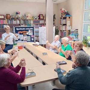 Seniorzy wraz z prowadzącą  wykonują ćwiczenia dłoni.