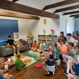 Spotkanie w bibliotece - młody chłopak czyta dzieciom książkę