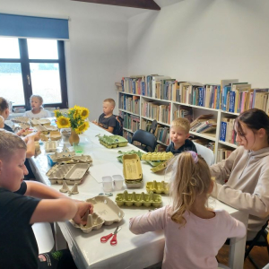 Uczestnicy warsztatów wykonują pracę plastyczną - zawieszkę słonecznik