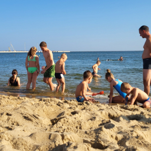 Dzieci wraz z opiekunami na plaży tuż przy brzegu morza