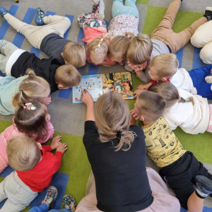 bibliotekarka czyta dzieciom ksiązke na dywanie.