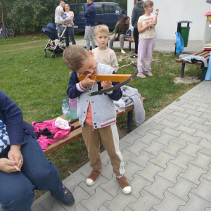 Uczestnicy pikniku, chłopiec strzela z kuszy.