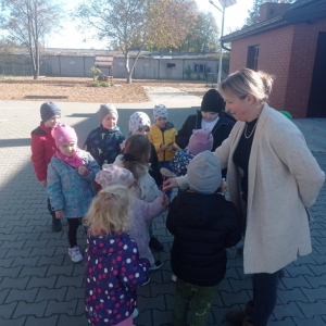 Bibliotekarka rozdaje dzieciom rekwizyty potrzebne do zabawy