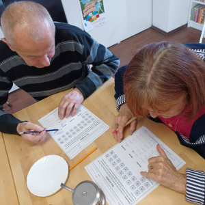 Para seniorów zapisuje na kartce rozwiązania do zadanych ćwiczeń