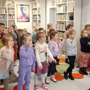 Grupa dzieci naśladuje gesty bibliotekarki śpiewającej piosenkę o misiu