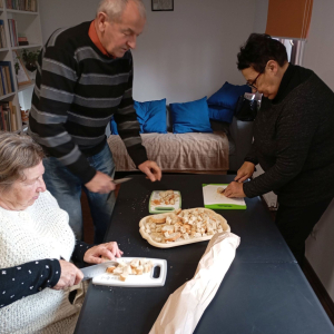 Troje uczestników przy stole kroją chleb na grzanki