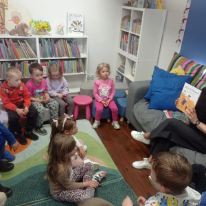 Bibliotekarka pokazuje dzieciom książkę, którą będzie czytała.
