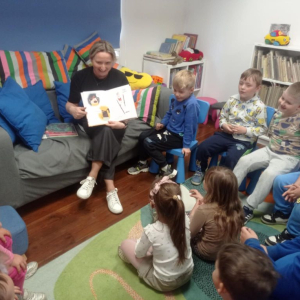 Bibliotekarka pokazuje dzieciom ilustracje w książce.