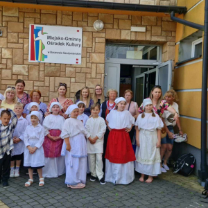 Opiekunowie i dzieci pozują do zdjęcia przed budynkiem domu kultury