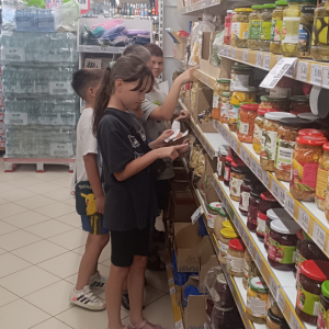 Dzieci oglądają towary na półce w sklepie spożywczym