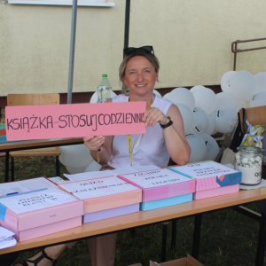 Bibliotekarka trzyma napis "Książka stosuj codziennie"