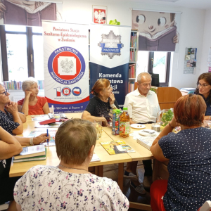 Funkcjonariuszka policji rozmawia z seniorami o bezpieczeństwie