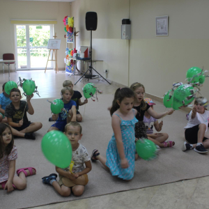 Chłopcy i dziewczęta siedzą na dywanie z balonami