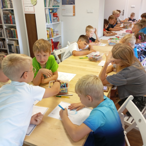 Uczestnicy warsztatów kolorują obrazek robota