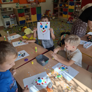 Mały chłopiec pokazuje swoją pracę, obok inne dzieci kończą swoje.