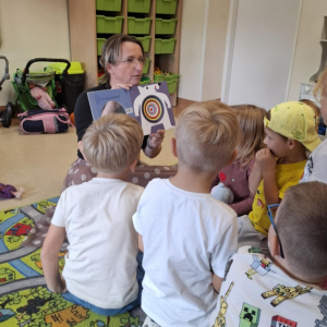 Bibliotekarka prezentuje i opowiada dzieciom o książce "Kto zjadł biedronkę"