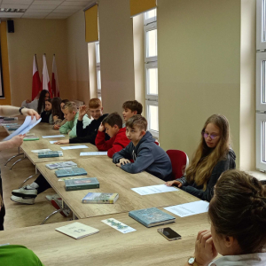 Prowadzący warsztaty rozdaje kartki uczestnikom, którzy uważnie słuchają i przygotowują się do kolejnego zadania.