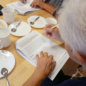 Kobieta pochylona nad kartką rozwiązuje ćwiczeniem