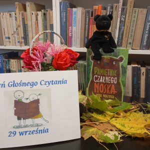 Wystawka promująca Dzień Głośnego Czytania (hasło, książka i czarny miś)
