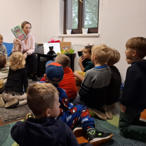 Bibliotekarka pokazuje dzieciom książkę.