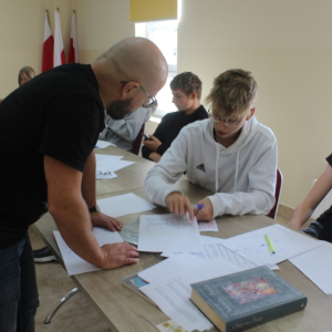 Chłopak pokazuje informację zapisaną na kartce prowadzącemu