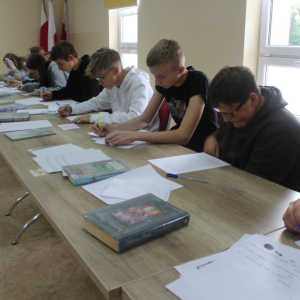 Młodzież siedząca przy stole czyta tekst na kartce