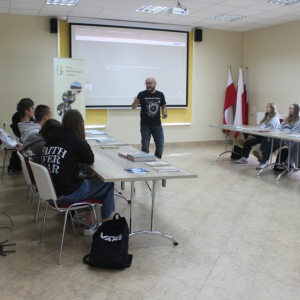 Uczestnicy siedzą w sali konferencyjnej