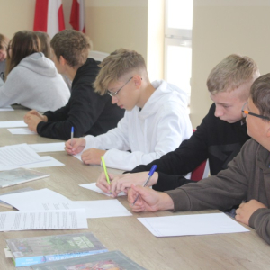 Trzechsiedzących przy stole chłopców notuje